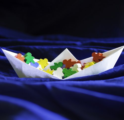Immigration emigration migration concept, paperboat with meeples