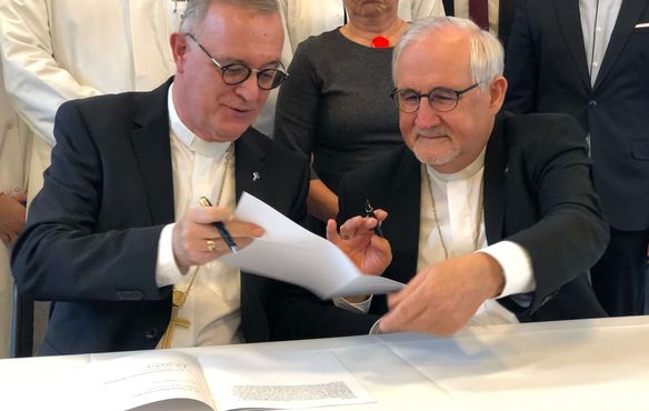 Landesbischof Dr. h. c. Frank Otfried July (l.) reicht die Rahmenvereinbarung zur Unterschrift an Bischof Dr. Gebhard Fürst weiter.