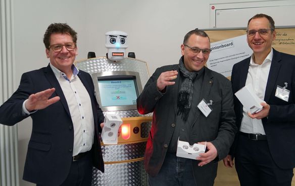 Auch die Geschäftsführer des Evangelischen Medienhauses setzen auf Digitalisierung: Dan Peter (v.l.), Tobias Glawion und Frank Zeithammer. Im Hintergrund der Segensroboter „BlessU-2“.