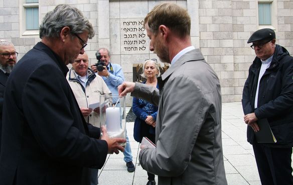 Vor der Stuttgarter Synagoge entzünden die beiden Synoden-Vizepräsidenten Werner Stepanek (l.) und Johannes Eißler eine Kerze als Zeichen der Solidarität der württembergischen Landeskirche mit der Israelitischen Religionsgemeinschaft in Württemberg sowie allen jüdischen Gemeinden. Landesbischof Dr. h.c. Frank Otfried July (r.) sowie Susanne Jakubowski und Michael Kashi vom israelitischen Gemeindevorstand und Rabbiner Jehuda Puschkin beobachten die Szene.