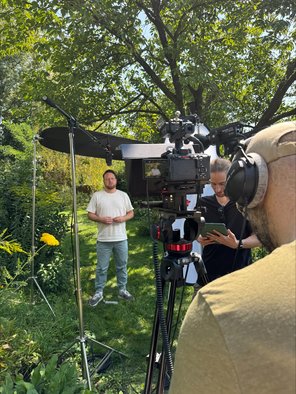 Zwei Kameramänner im Garten, im Hintergrund Tobias Wörner bei Filmaufnahme